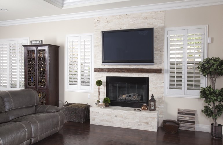White plantation shutters in a San Antonio living room with plank hardwood floors.